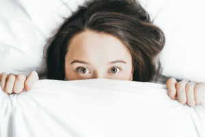 Mujer en cama tapánsose la cara